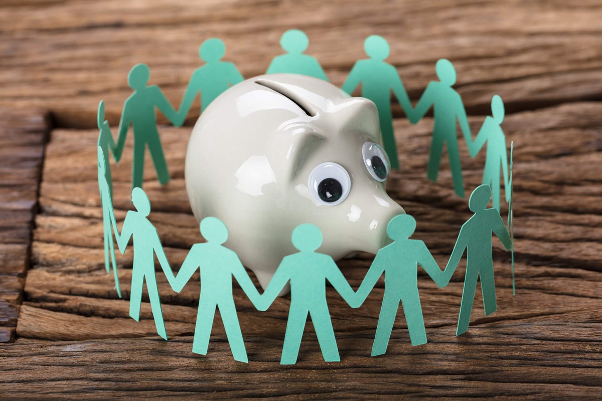 humans holding hands around a piggy bank