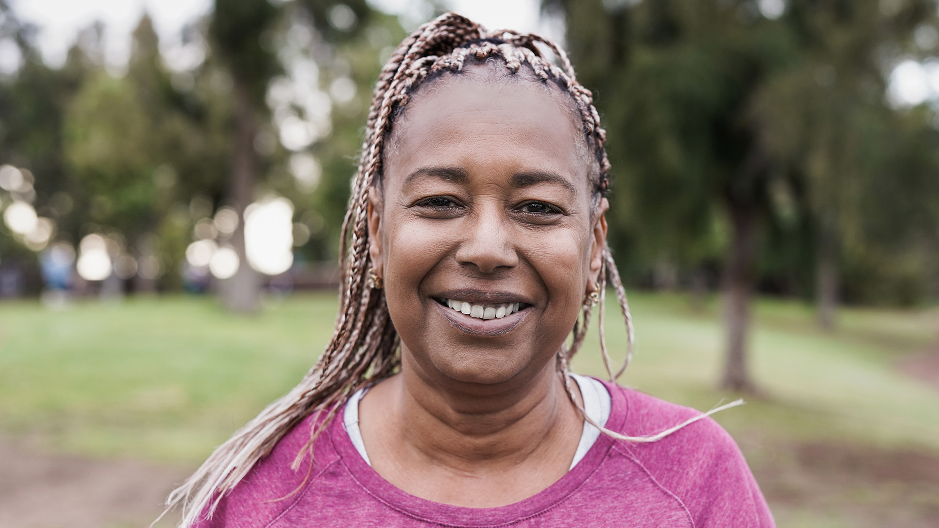 Woman smiling at the camera with trees in the background