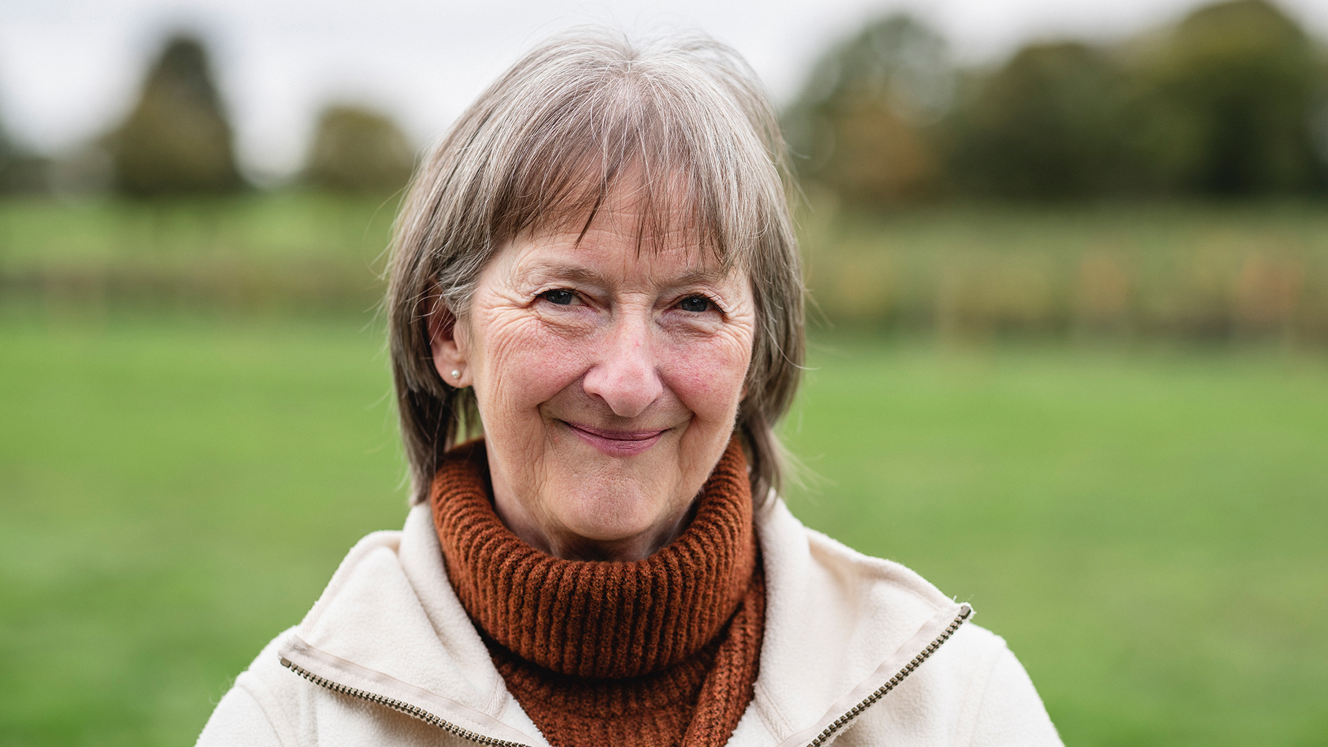 Woman smiling at the camera in a grassy field