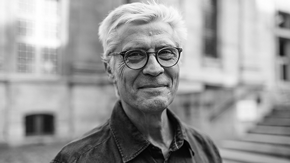 White haired man with glasses looking at camera
